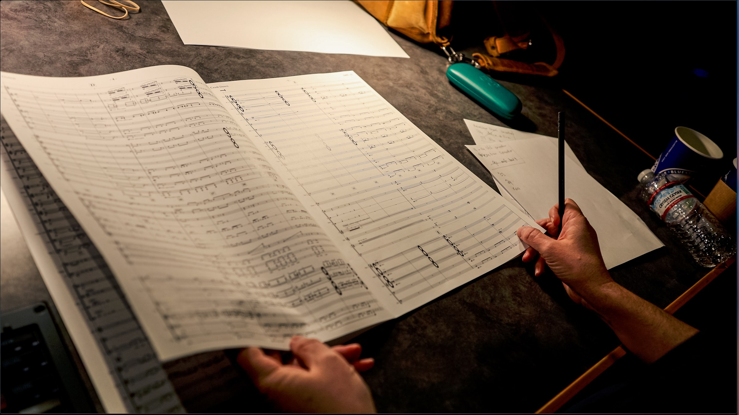A hand marking an orchestral score during a recording session
