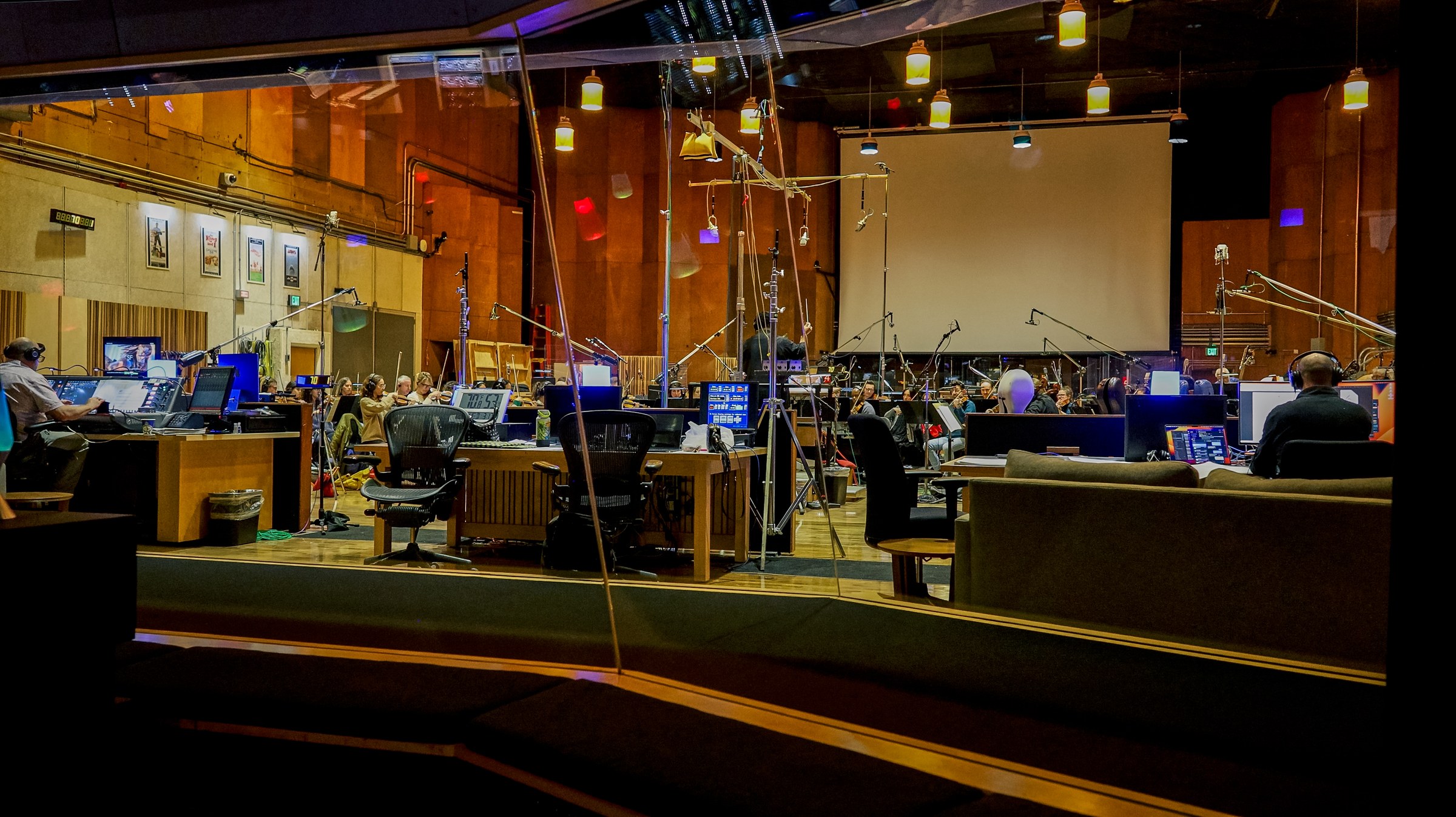 A large orchestral recording session viewed from the control room